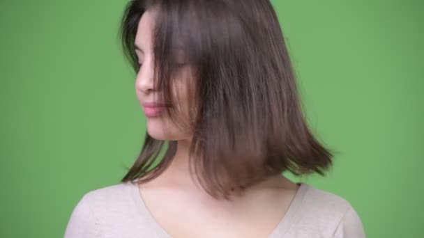 Mooie jongedame niet knikken tegen groene achtergrond — Stockvideo