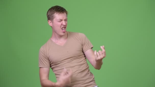 Young handsome Scandinavian man playing air guitar — Stock Video