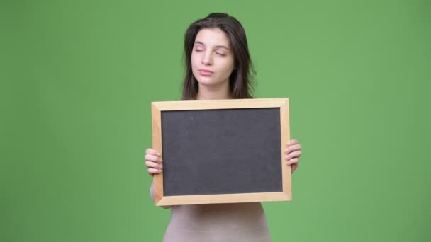 Junge schöne Frau denkt, während sie die Tafel hält — Stockvideo