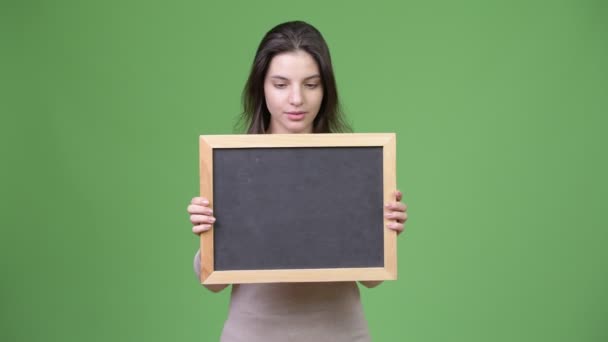Junge schöne Frau sieht schockiert aus, während sie eine Tafel hält — Stockvideo