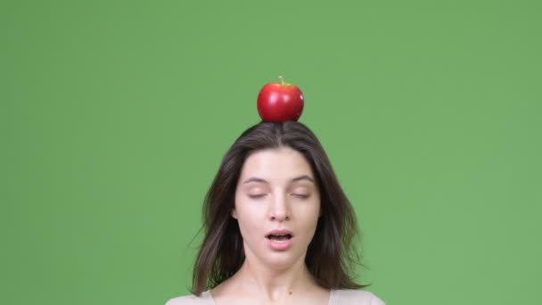 Κοντινό πλάνο του νεαρή όμορφη γυναίκα με το μήλο στο κεφάλι — Αρχείο Βίντεο