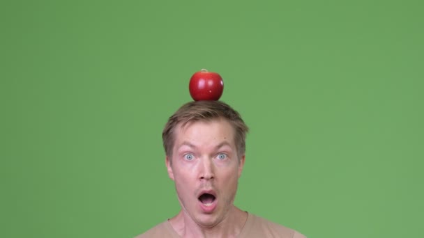 Primer plano de joven apuesto hombre escandinavo con manzana en la cabeza — Vídeos de Stock