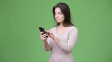 Telefon yeşil arka plana karşı kullanan genç güzel kadın