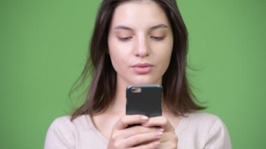 Telefon yeşil arka plana karşı kullanan genç güzel kadın