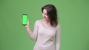 Genç mutlu güzel kadın gösteren telefon yeşil bir arka plana dayanır