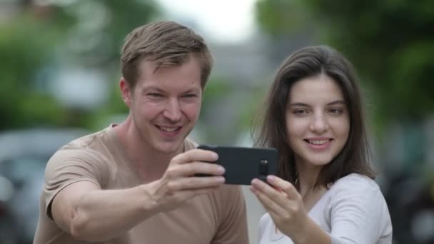 Νεαρό ζευγάρι ευτυχισμένο λαμβάνοντας αυτοπορτρέτα μαζί στους δρόμους σε εξωτερικούς χώρους — Αρχείο Βίντεο