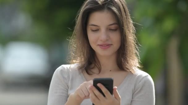 Mladá šťastná krásná žena pomocí telefonu v ulicích venku — Stock video
