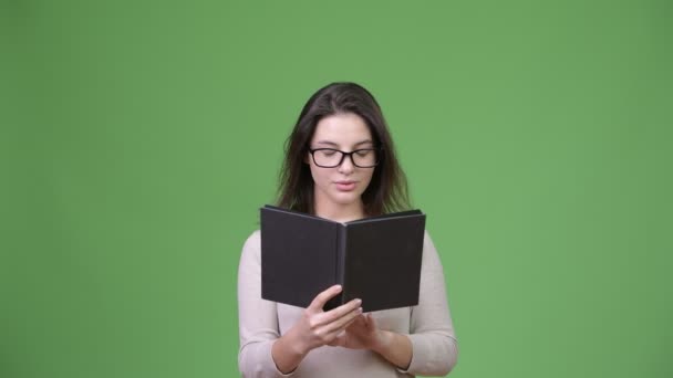 Joven hermosa mujer mirando sorprendido mientras estudia — Vídeo de stock