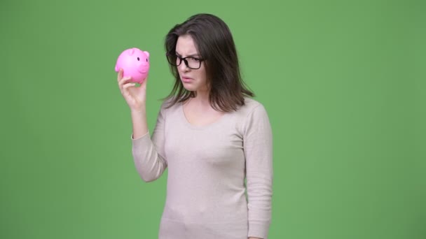 Young beautiful woman shaking piggy bank — Stock Video