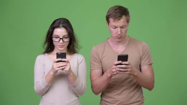 年轻夫妇使用电话在一起反对绿色背景 — 图库视频影像