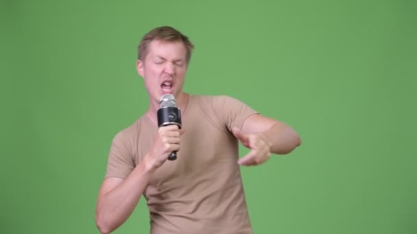 Молодой красивый скандинавский мужчина поет на зеленом фоне — стоковое видео