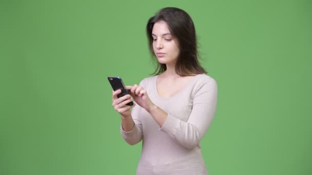 Young beautiful woman using phone against green background — Stock Video