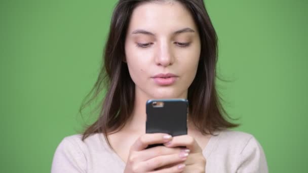 Junge schöne Frau mit Telefon vor grünem Hintergrund — Stockvideo