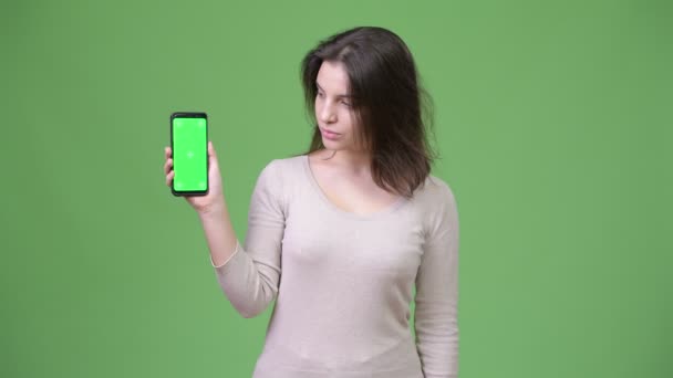 Mooie jongedame weergegeven: telefoon tegen groene achtergrond — Stockvideo