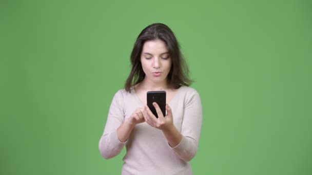 Joven hermosa mujer mirando sorprendido mientras se utiliza el teléfono — Vídeo de stock