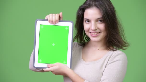 Jeune heureuse belle femme souriante tout en montrant tablette numérique — Video