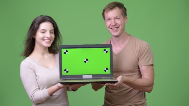 Jovem casal feliz sorrindo ao mostrar laptop juntos — Vídeo de Stock