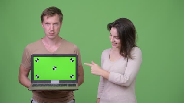 Unga par visar laptop och pekande finger tillsammans — Stockvideo