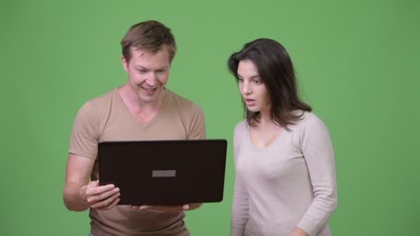 Νεαρός άνδρας που χρησιμοποιούν φορητό υπολογιστή με νεαρή γυναίκα που αναζητούν σοκαρισμένος — Αρχείο Βίντεο