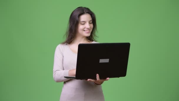 Joven feliz hermosa mujer sonriendo mientras usa el ordenador portátil — Vídeos de Stock