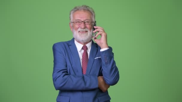 Handsome senior bearded businessman against green background — Stock Video