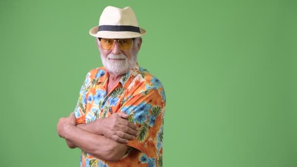 Handsome senior bearded tourist man ready for vacation against green background — Stock Video