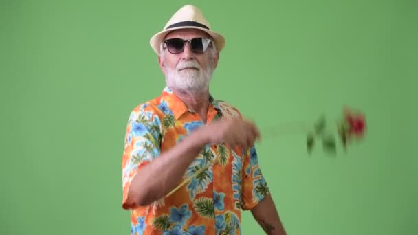 Handsome senior bearded tourist man ready for vacation against green background — Stock Video