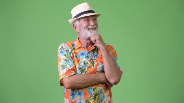 Handsome senior bearded tourist man ready for vacation against green background — Stock Video