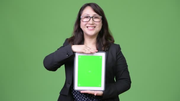 Mature beautiful Asian businesswoman showing digital tablet — Stock Video