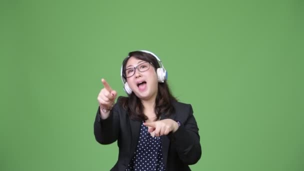 Зрелая красивая азиатская бизнесвумен слушает музыку — стоковое видео