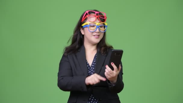 Madura hermosa mujer de negocios asiática utilizando el teléfono mientras usa muchas gafas como concepto divertido — Vídeo de stock