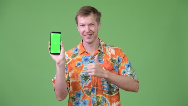 Молодий красивий турист показує телефон і дає великі пальці вгору — стокове відео