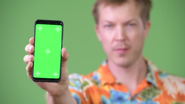 Jonge gelukkig knap toeristische man die lacht terwijl het tonen van de telefoon — Stockvideo