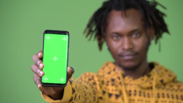 Unga glada stilig afrikanska man ler medan visar telefonen — Stockvideo