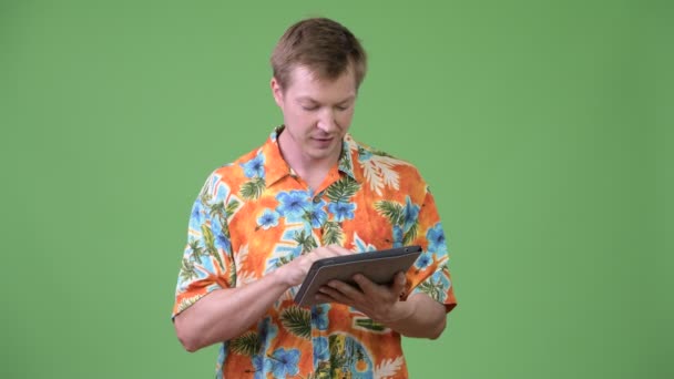 Young happy handsome tourist man using digital tablet and thinking — Stock Video