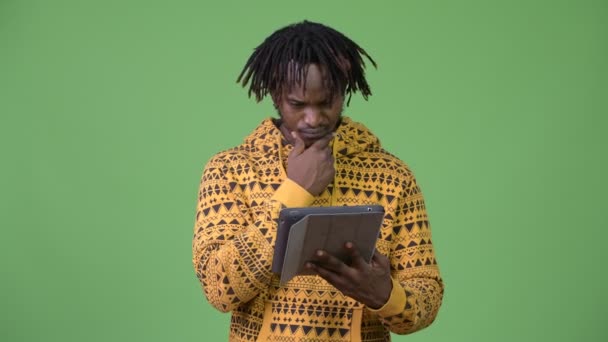 Jonge knappe Afrikaanse man met behulp van digitale tablet en denken — Stockvideo