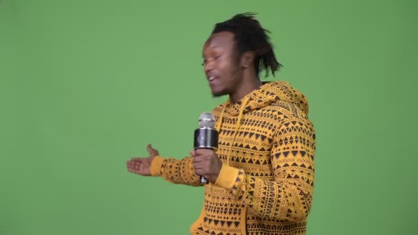 Joven hombre africano guapo hablando en el micrófono y mostrando algo — Vídeo de stock