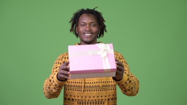 Young handsome African man giving gift box — Stock Video