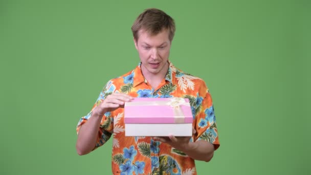 Jovem bonito turista homem caixa de presente de abertura e olhando surpreso — Vídeo de Stock