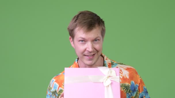Joven hombre turístico guapo sonriendo mientras que da caja de regalo — Vídeos de Stock