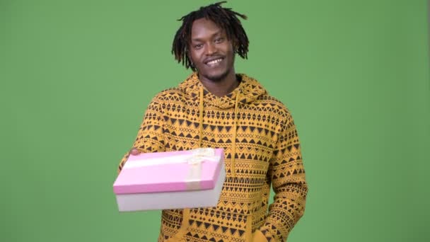 Young happy handsome African man giving gift box — Stock Video