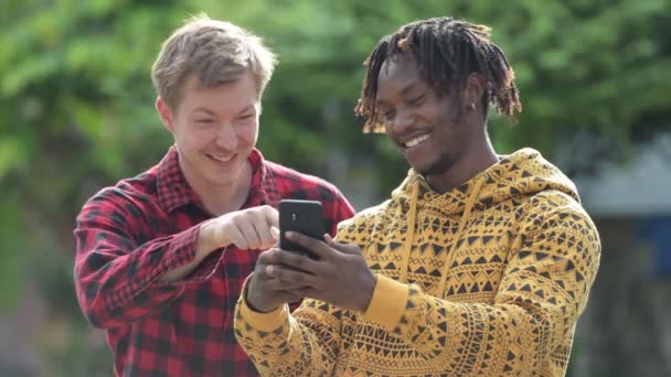 Jeunes amis multiethniques utilisant le téléphone ensemble dans les rues à l'extérieur — Video