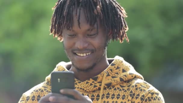 年轻快乐英俊非洲人微笑着, 而使用手机在街上户外 — 图库视频影像