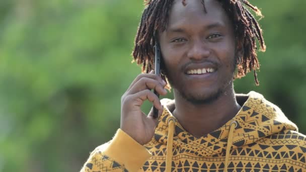 Молодой счастливый красивый африканский мужчина улыбается, когда зовет на улицу — стоковое видео