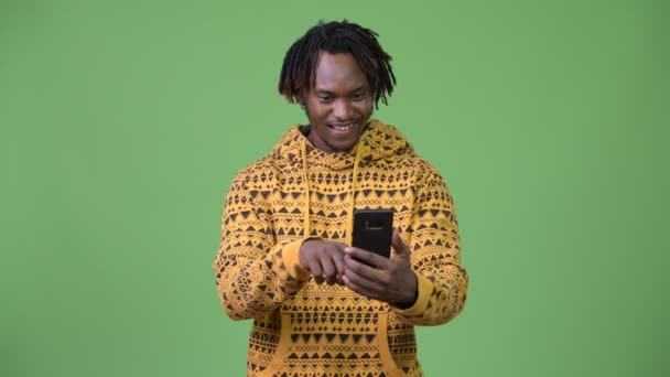 Joven hombre africano guapo usando el teléfono y recibiendo buenas noticias — Vídeos de Stock