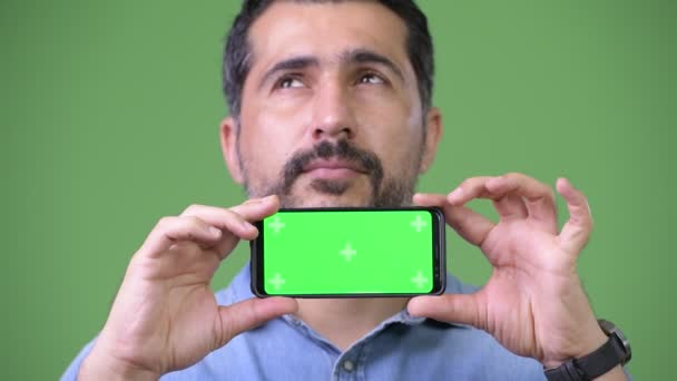 Красивый персидский бородатый мужчина показывает телефон и думает: — стоковое видео