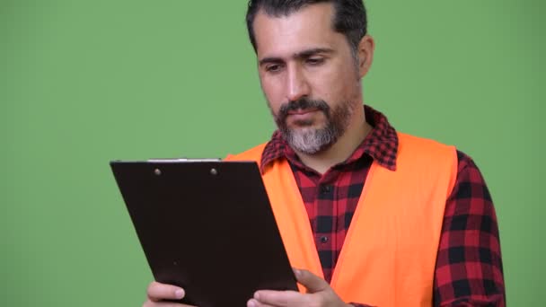 Szép perzsa szakállas ember építőipari munkás olvasó csipeszes írótábla — Stock videók