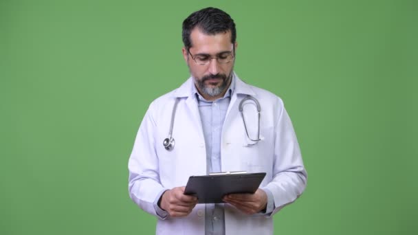 Guapo persa barbudo médico hombre leyendo portapapeles — Vídeos de Stock
