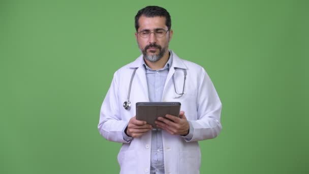 Handsome Persian bearded man doctor thinking while using digital tablet — Stock Video