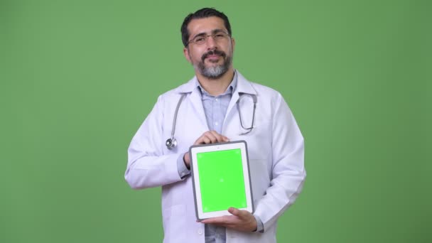 Beau perse barbu homme médecin montrant tablette numérique — Video